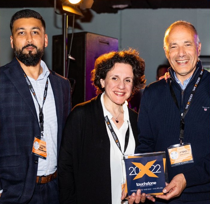 Two men and one women employees of TouchstoneBI smile at the camera holding theTimeXtender 2022 Partner of the year award in their hands