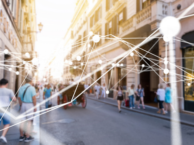 People walking down a street with lines representing a network connected to them.
