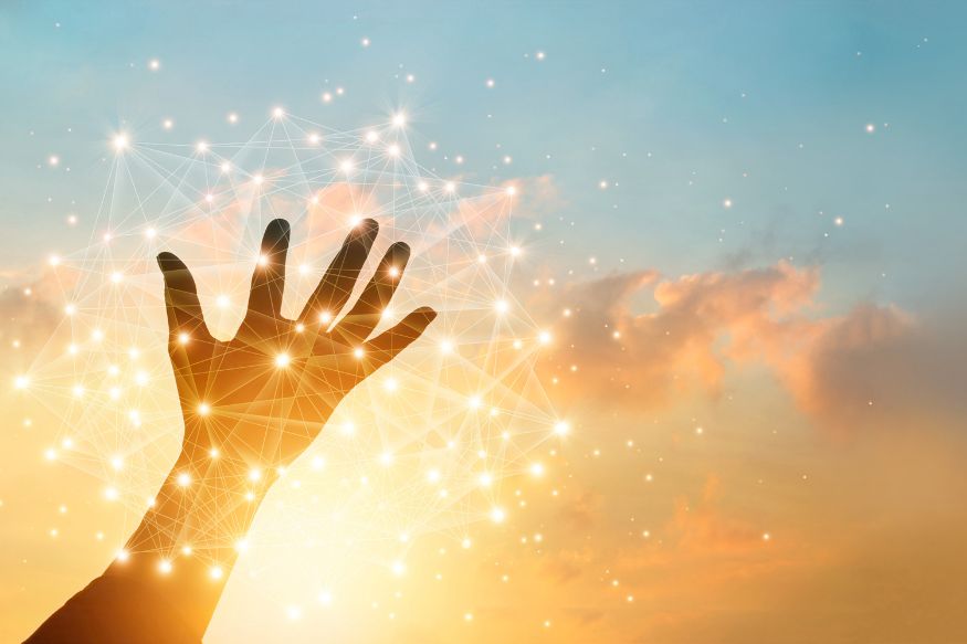 A person's hand reaching up to a starry evening sky.