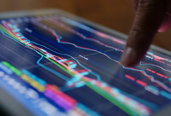 A finger pointing at a line on a graph displayed on a tablet screen.