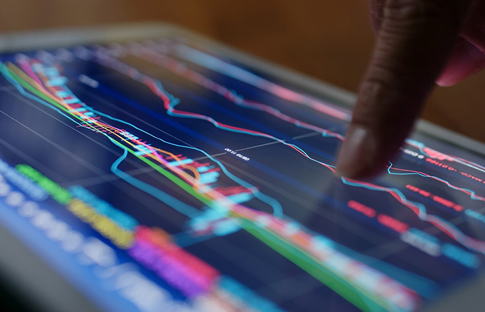 A finger pointing at a line on a graph displayed on a tablet screen.