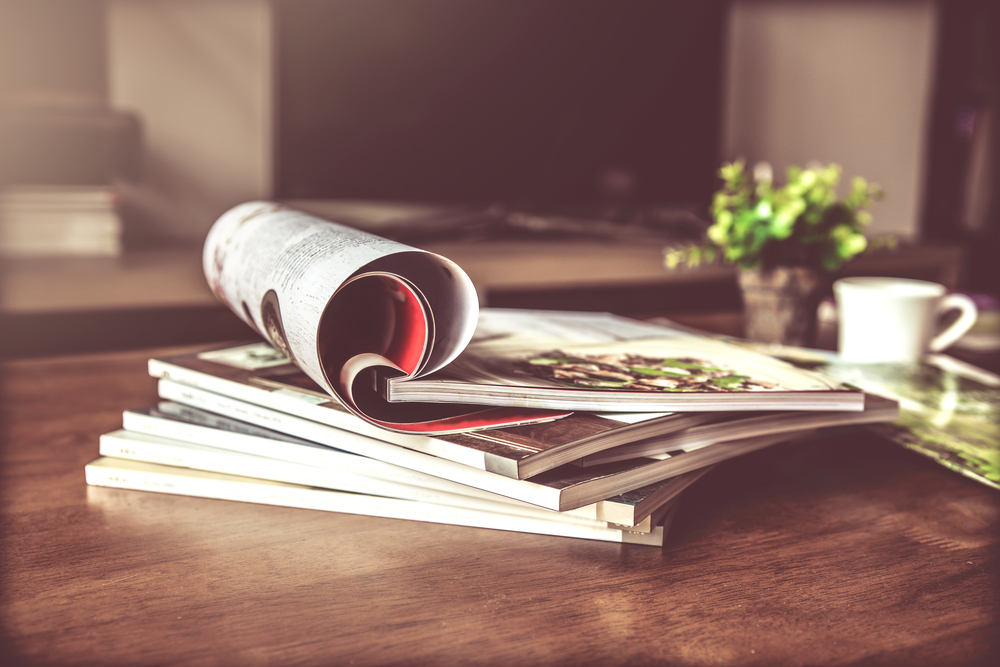 Photograph of a stack of magazines in a living room.